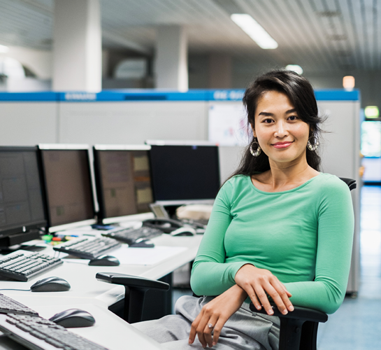 femme souriante devant plusieurs écrans d'ordinateur