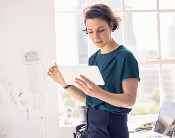 femme dans un bureau ensoleillé travaillant sur sa tablette