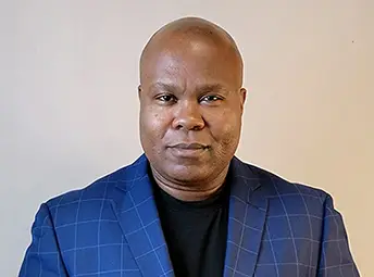 Black bald men wearing a blue plaid jacket on grey background