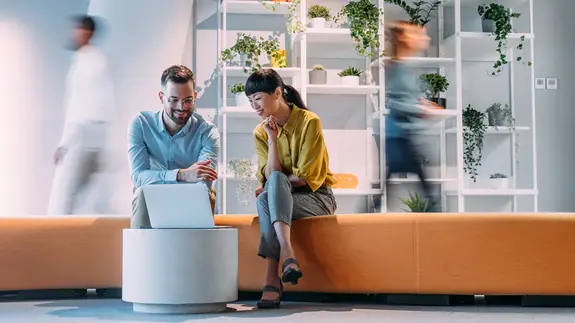 un homme et une femme collègues assis et regardant un ordinateur portable
