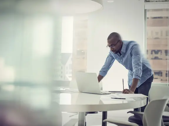 black businessman working in a brightly-lit office on a computer